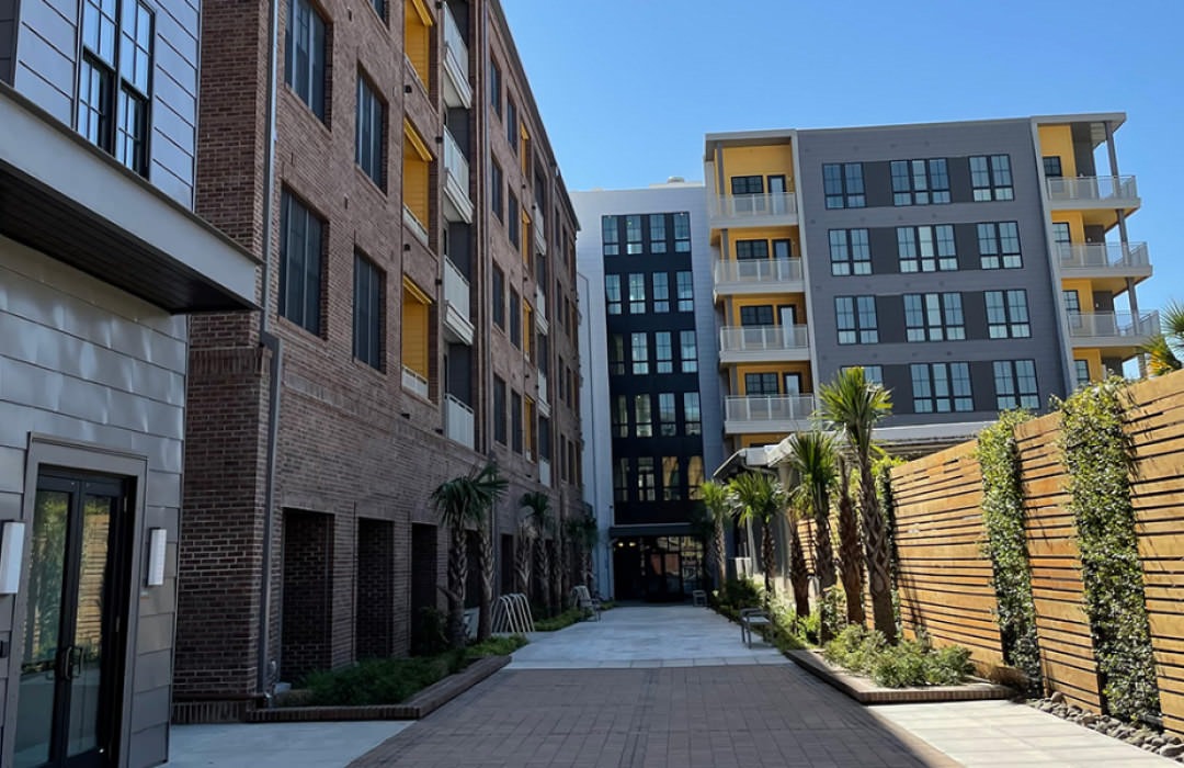 brick paved walk way between wood slated wall and residential buildings